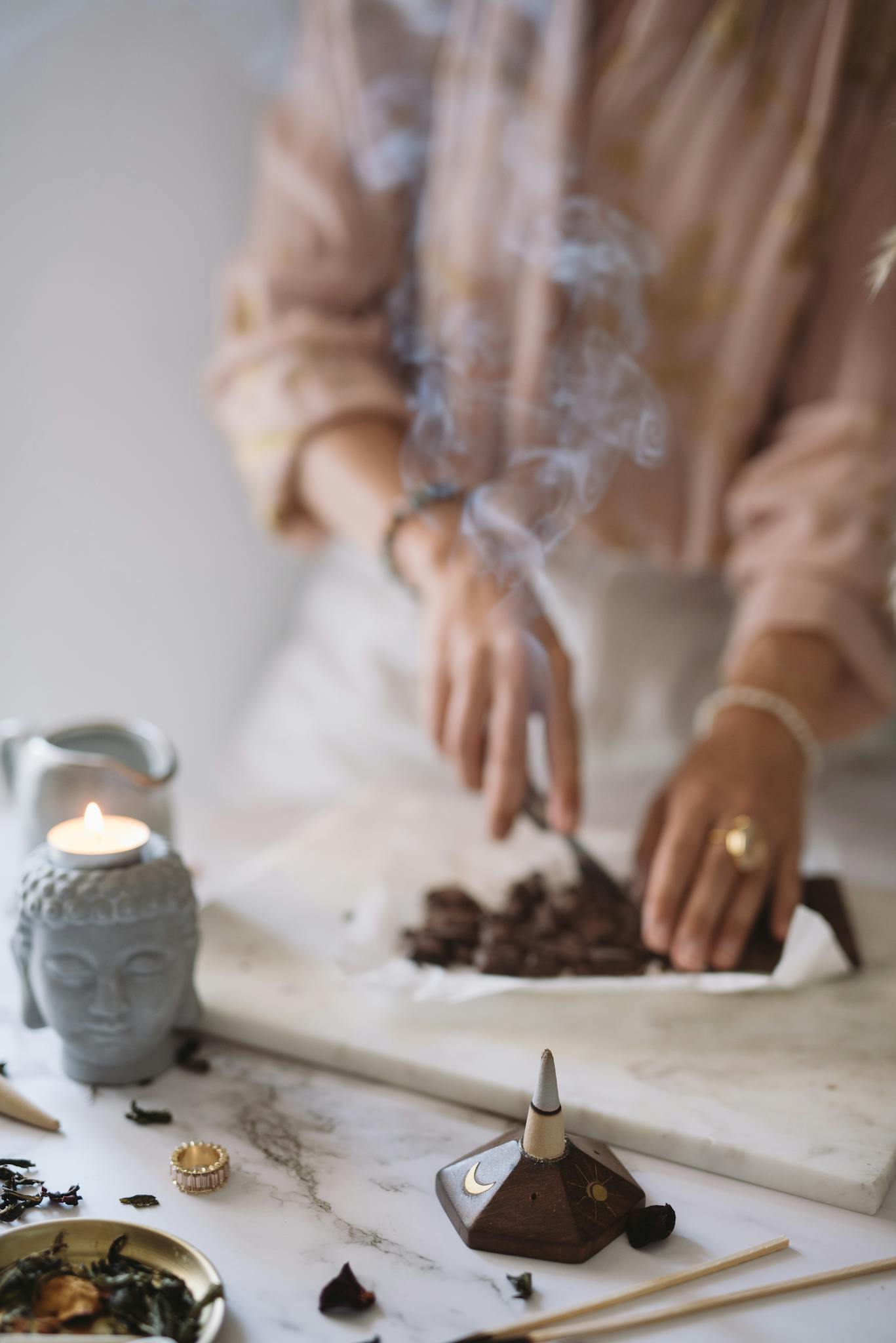 A serene setup with a woman cutting cacao, surrounded by aromatic candles and incense for a calming atmosphere.